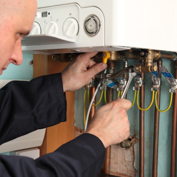 Plumber fixing a boiler on home visit