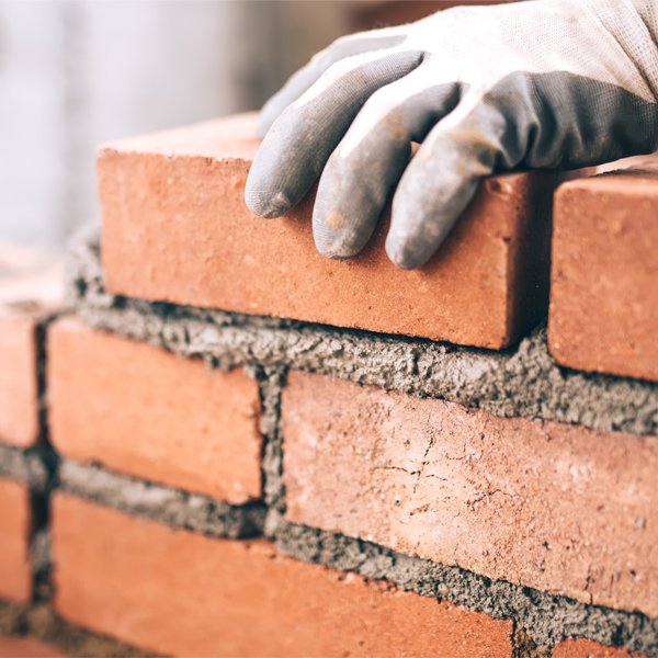 Worker adding brick to small wall